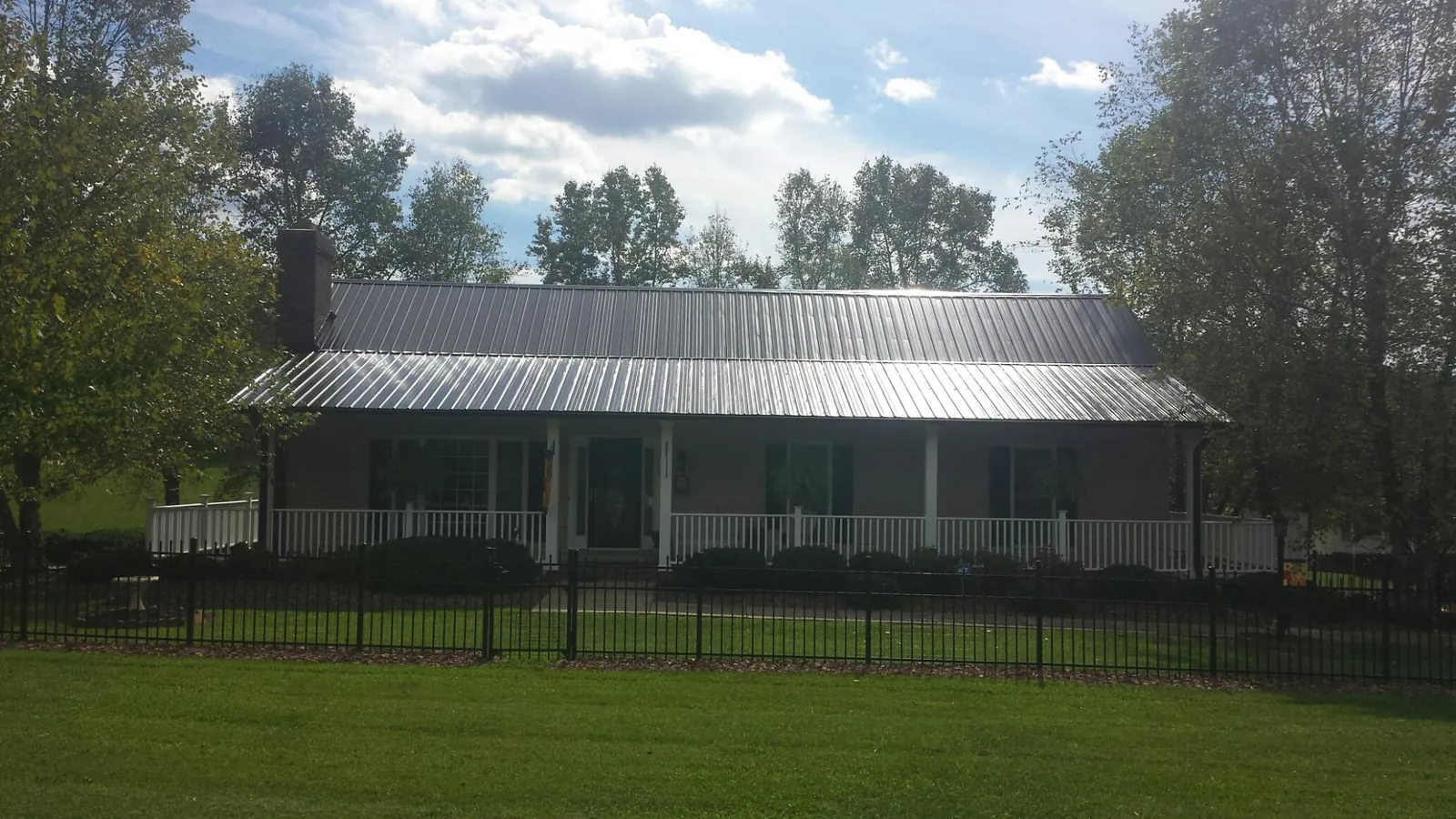 Gray metal roof on a brick ranch with a full width front porch — Gutter Guard Installation work by our crew in Jennings