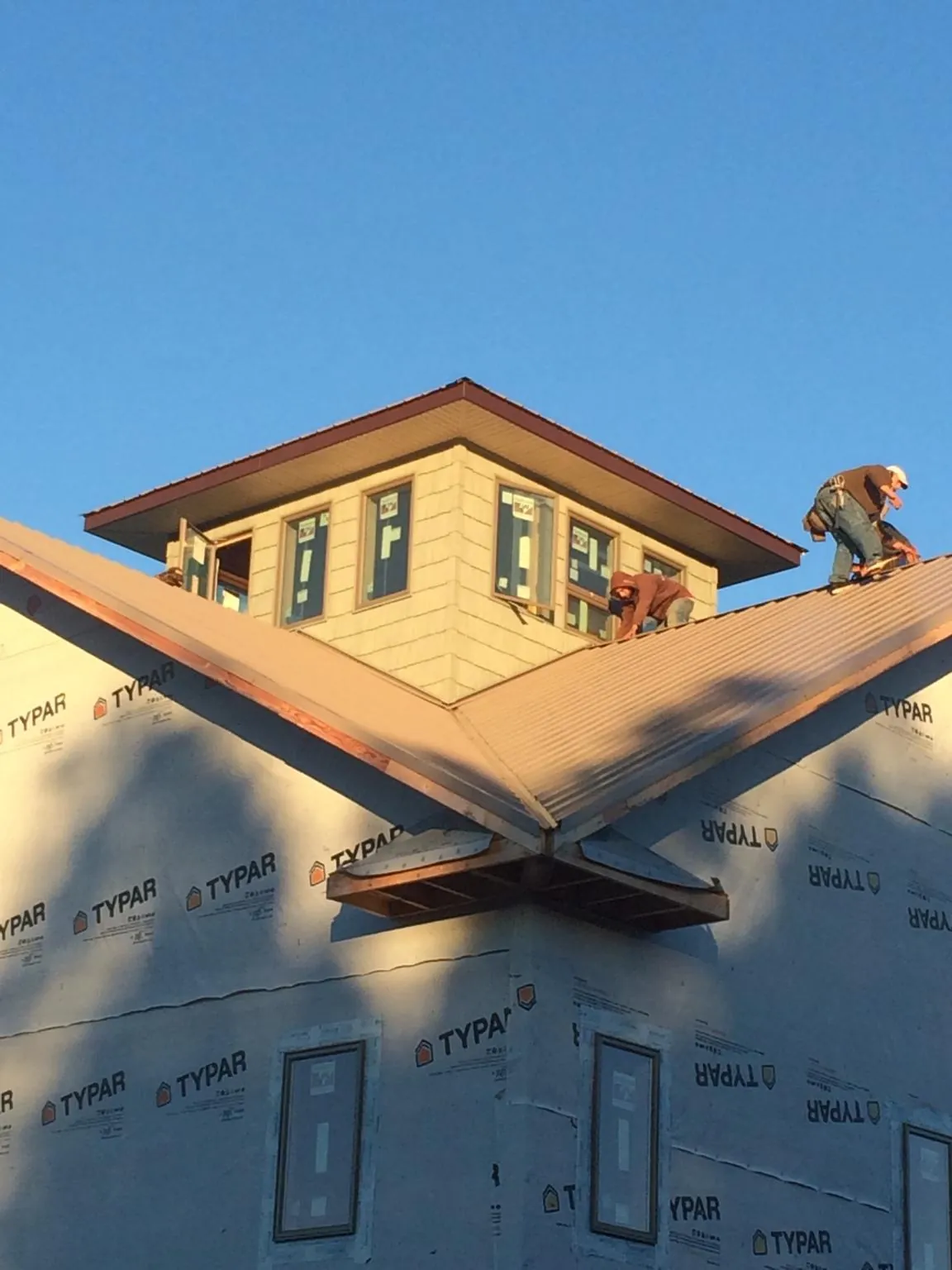 Roofers working around a rooftop cupola on a new metal roof at sunset — Roof Waterproofing in Jennings by Roofing Brothers